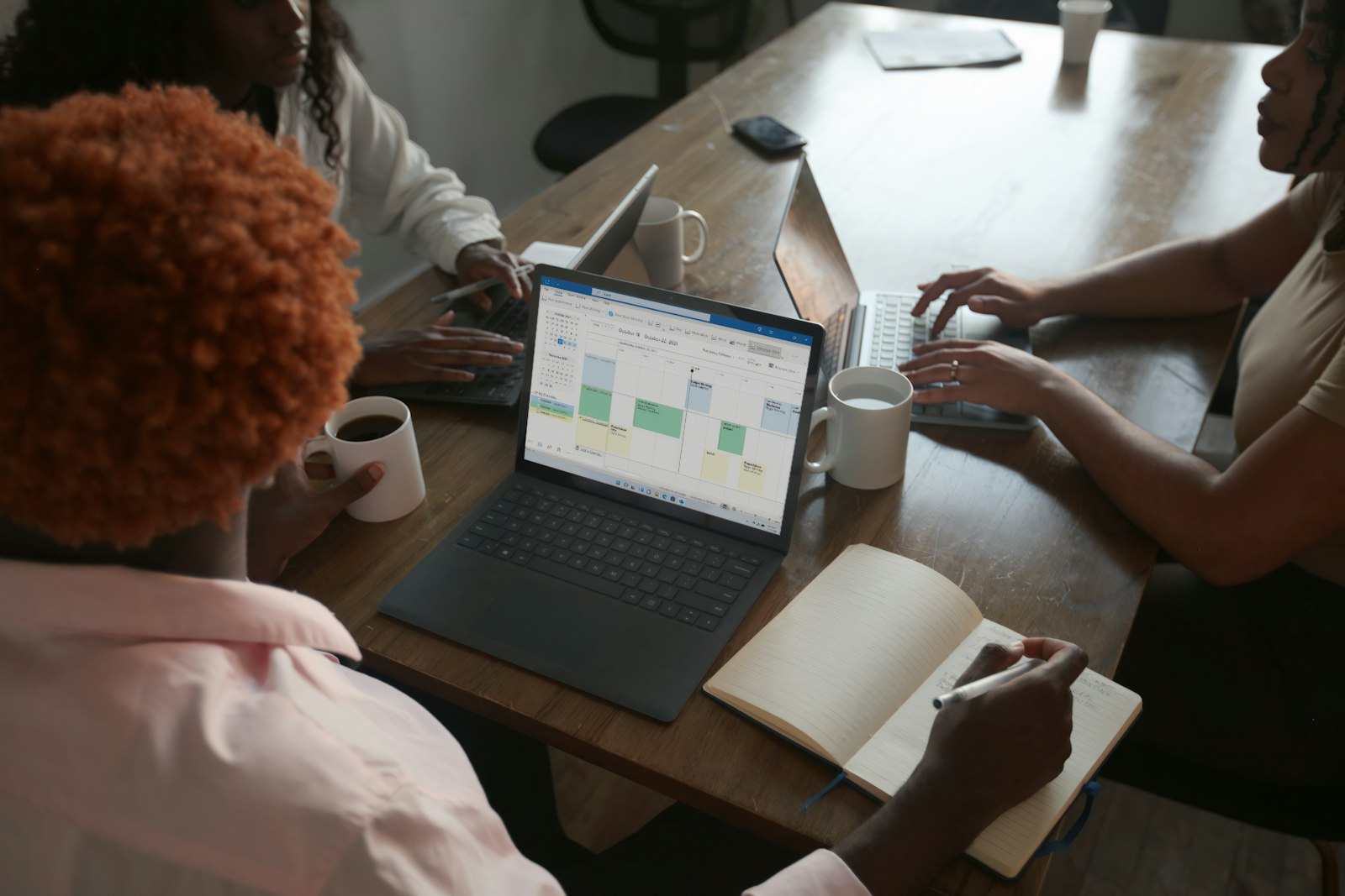 Equipe reunida discutindo cronograma em laptop, foto real