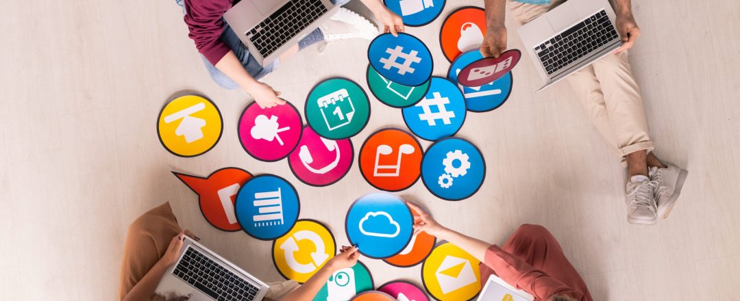 Above view of young social media marketers sitting on floor and using computers while analyzing marketing tools